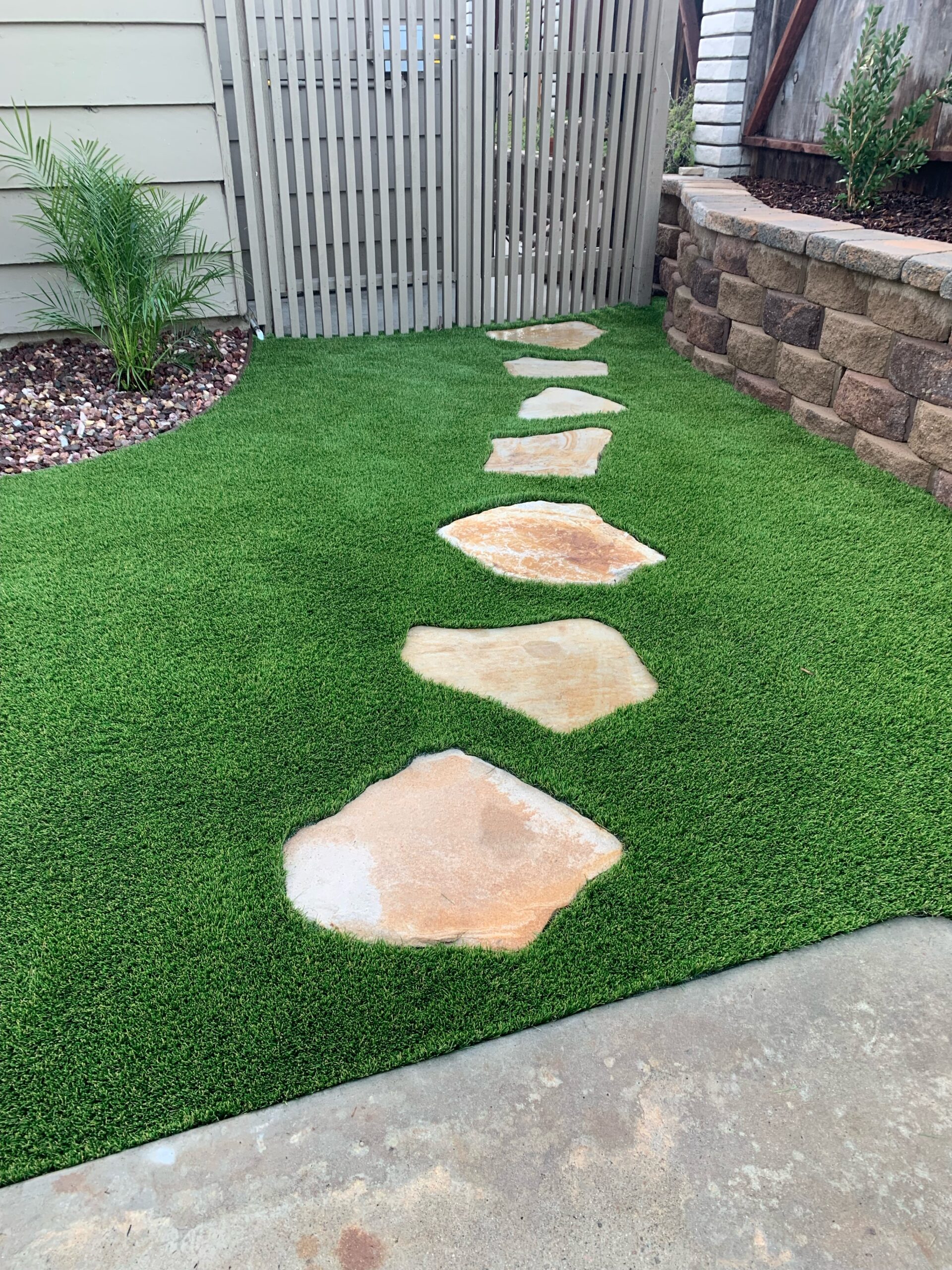 Residential turf installation with flagstone stepping stones and retaining wall block border