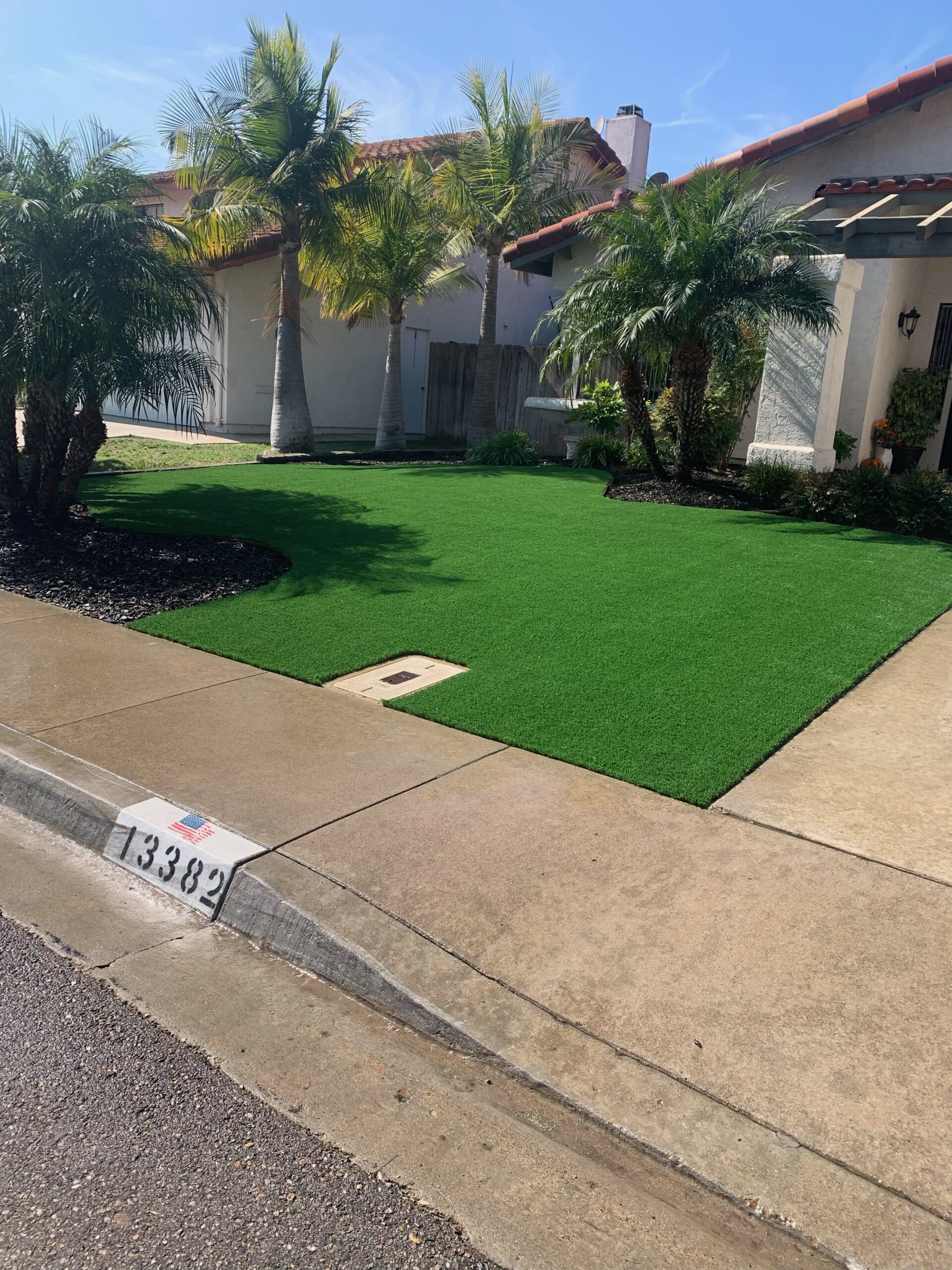 Front yard with vibrant turf and palms beside Mediterranean home exterior
