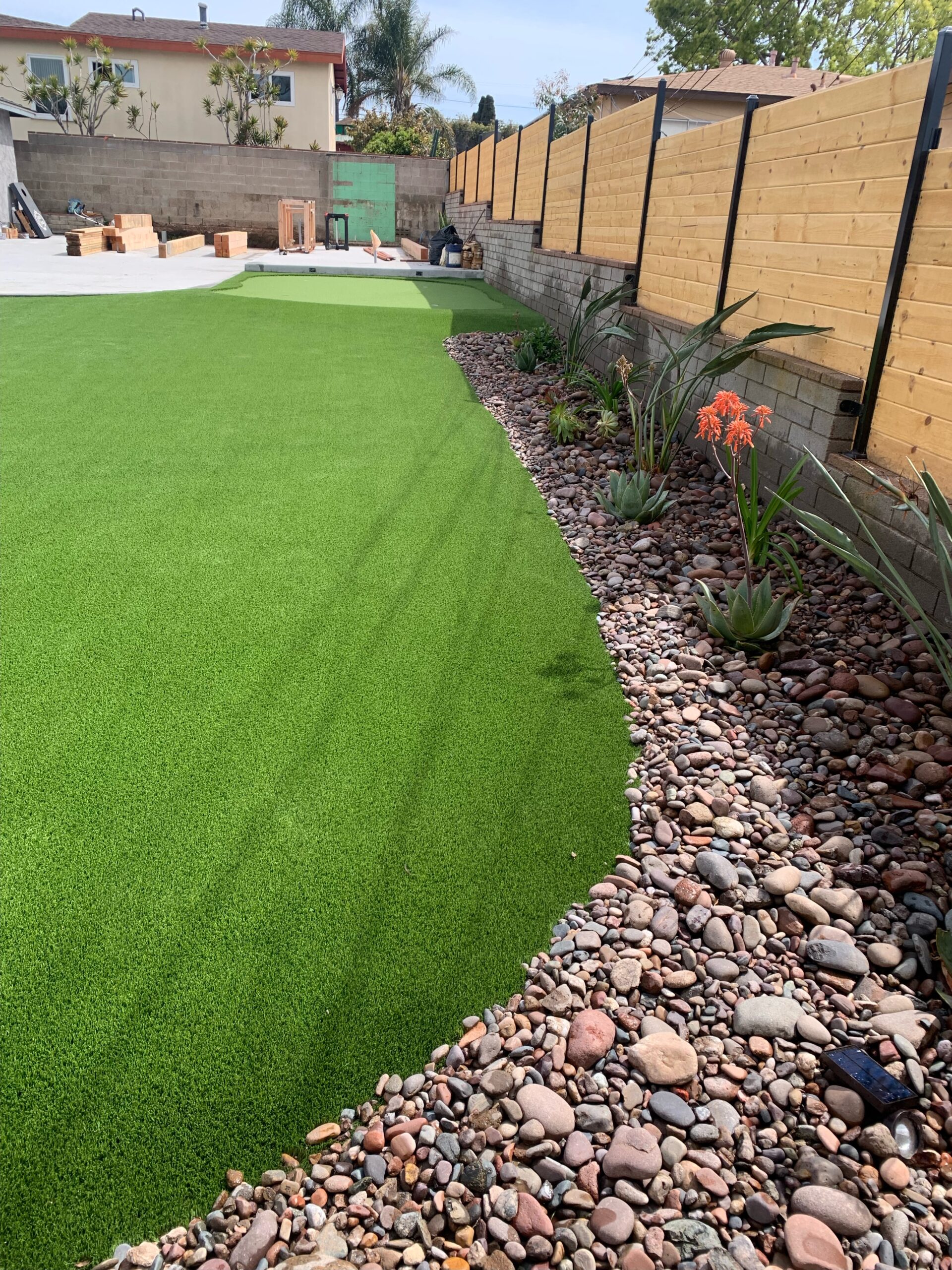Curved organic turf lawn bordered with river rock and succulents